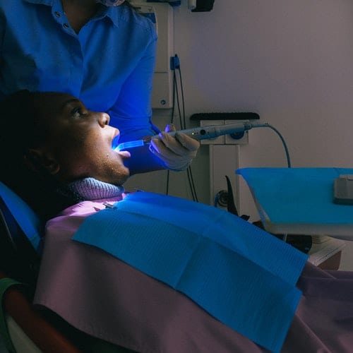 Dentist checking teeth with blue rays